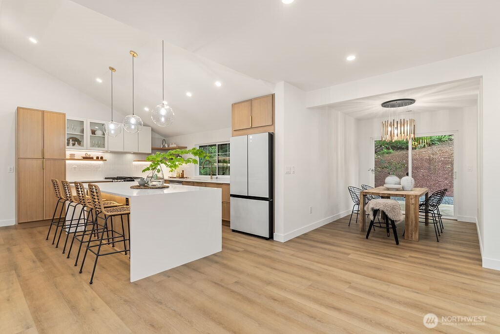 19433 Southeast 128th Street Renton, WA 98059 - Photo 22 of 40 a kitchen with kitchen island a refrigerator a stove a dining table and chairs with wooden floor