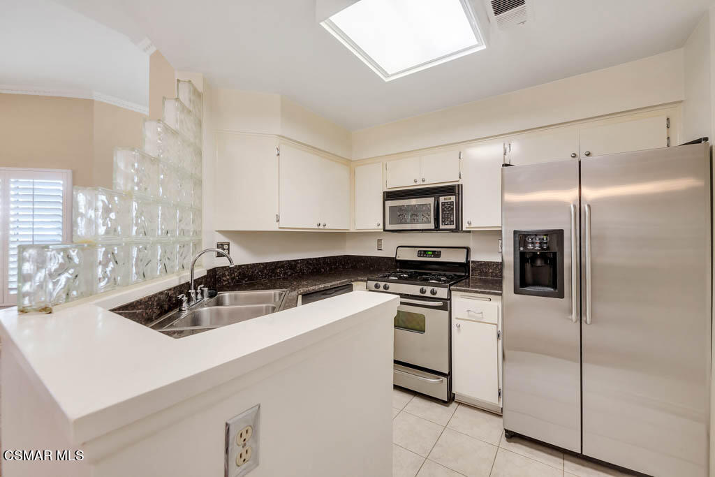 1736 Sinaloa Road, Unit 324 Simi Valley, CA 93065 - Photo 4 of 37 a kitchen with white cabinets and stainless steel appliances