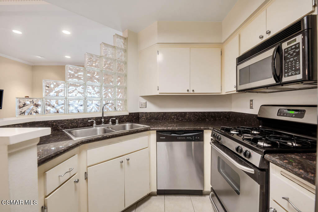 1736 Sinaloa Road, Unit 324 Simi Valley, CA 93065 - Photo 5 of 37 a kitchen with granite countertop white cabinets and stainless steel appliances