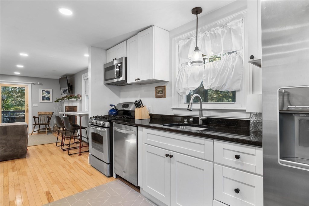117 May Brook Road Holland, MA 01521 - Photo 10 of 30 a kitchen with stainless steel appliances granite countertop a sink a stove oven a counter top space cabinets and living room view