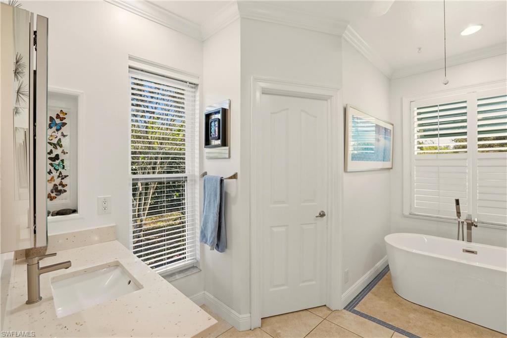 11180 Phoenix Way Naples, FL 34119 - Photo 18 of 43 Full bathroom featuring a freestanding tub, light tile patterned floors, crown molding, and vanity