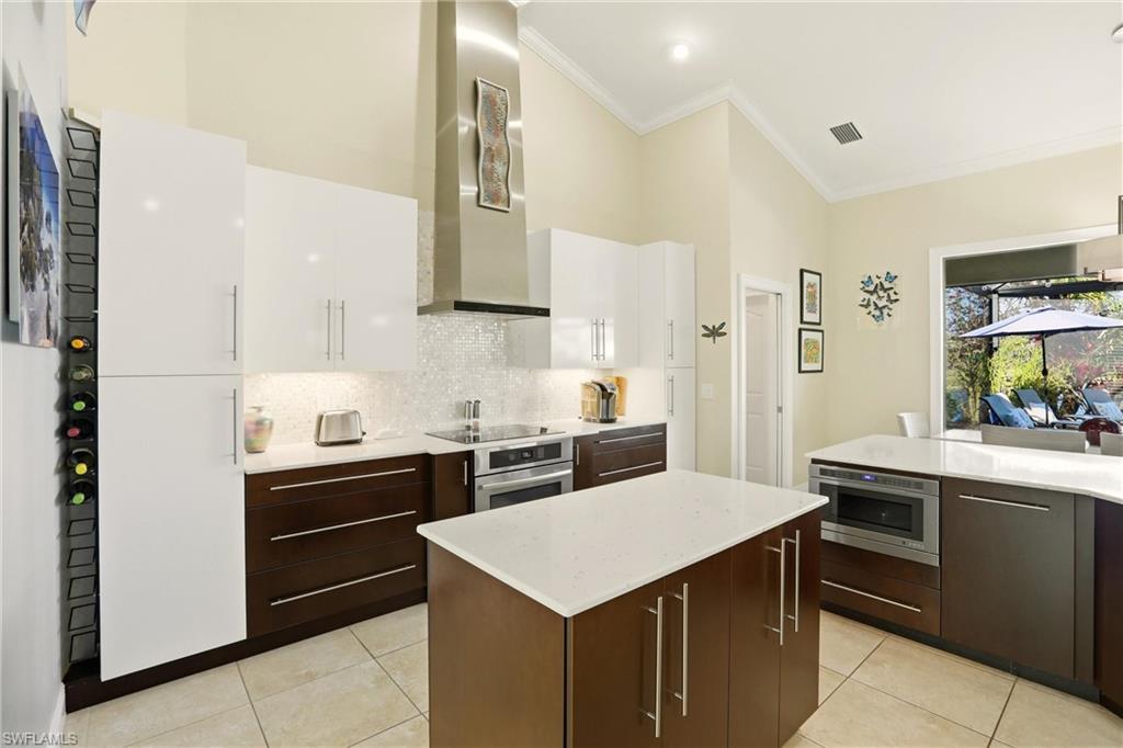 11180 Phoenix Way Naples, FL 34119 - Photo 8 of 43 Kitchen featuring backsplash, two tone cabinetry, a kitchen island, oven, and light tile patterned floors