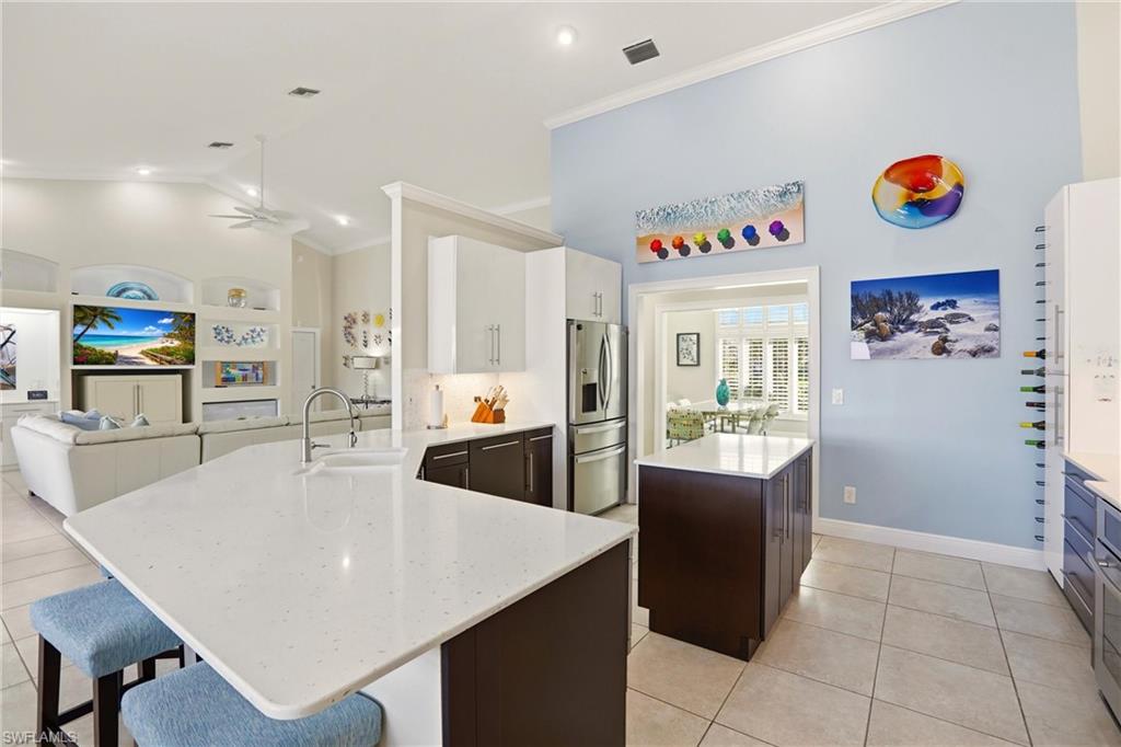11180 Phoenix Way Naples, FL 34119 - Photo 10 of 43 Kitchen with a center island, a peninsula, a ceiling fan, light tile patterned floors, and ornamental molding