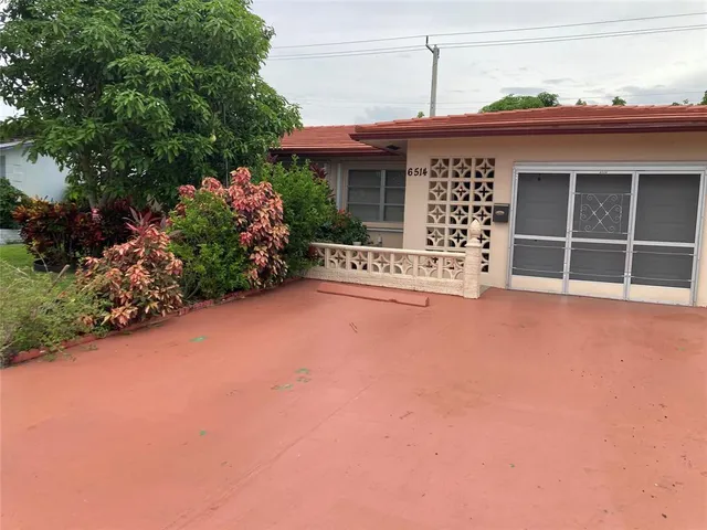 a front view of a house with a large window and potted plants