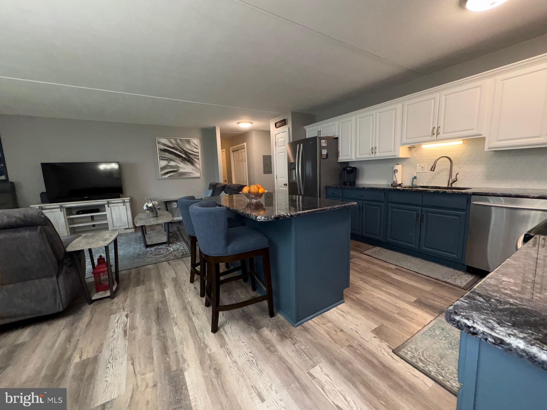 84 Welsh Tract Road, Unit 106 Newark, DE 19713 - Photo 12 of 32 a kitchen with granite countertop a sink dishwasher a stove top oven a dining table and chairs with wooden floor