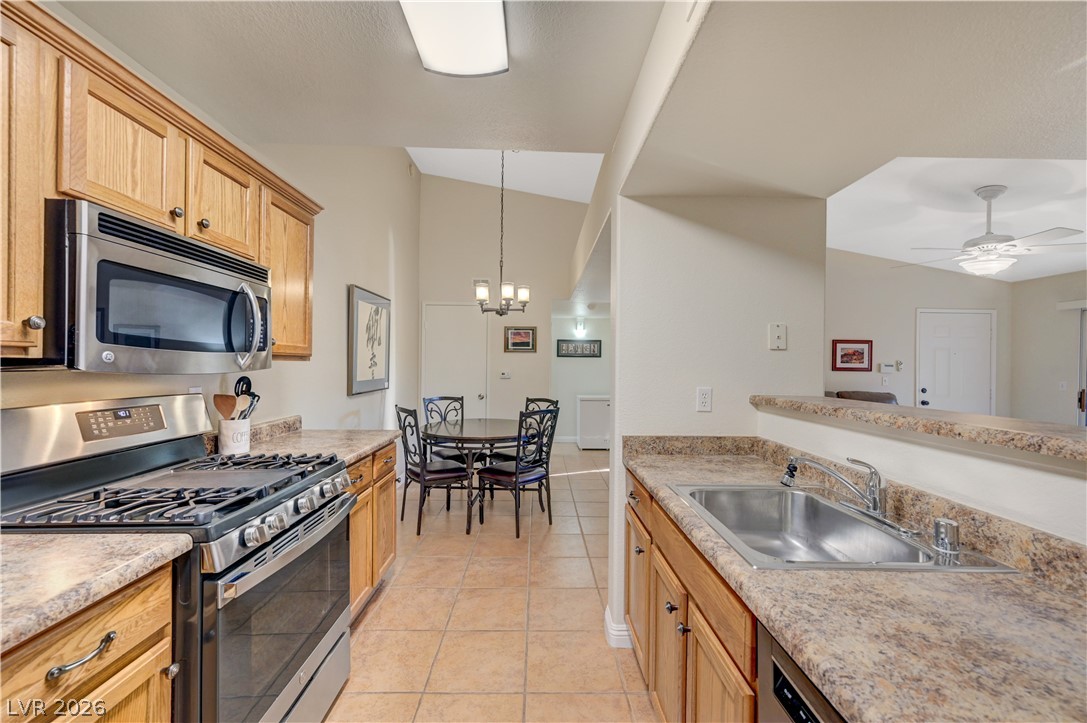 Kitchen featuring stainless steel appliances, a ceiling fan, light countertops, light tile patterned flooring, and a chandelier