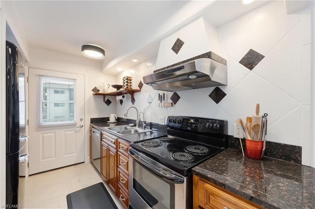 72 7th Street South, Unit 206 Naples, FL 34102 - Photo 10 of 38 a kitchen with a stove and a wooden cabinets