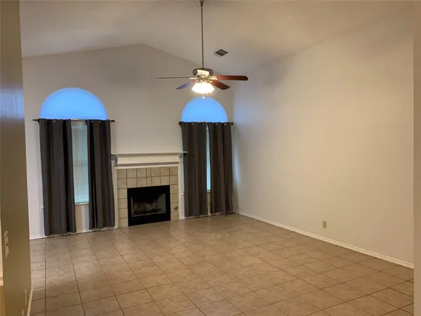 a view of an empty room with a fireplace and a chandelier fan
