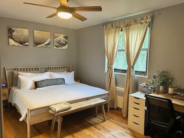 199-39 19th Avenue, Unit UPPR Queens, NY 11360 - Photo 12 of 16 Bedroom with light wood-style flooring, a ceiling fan, a desk, and radiator heating unit