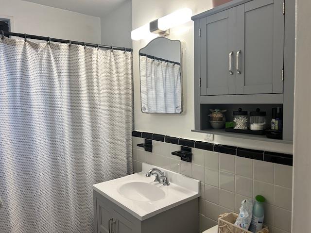 199-39 19th Avenue, Unit UPPR Queens, NY 11360 - Photo 14 of 16 Bathroom featuring vanity, tile walls, a shower with shower curtain, and a wainscoted wall