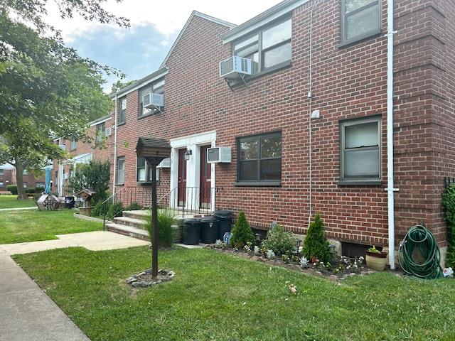 199-39 19th Avenue, Unit UPPR Queens, NY 11360 - Photo 2 of 16 View of front of house featuring brick siding, a front lawn, a wall mounted air conditioner, and cooling unit