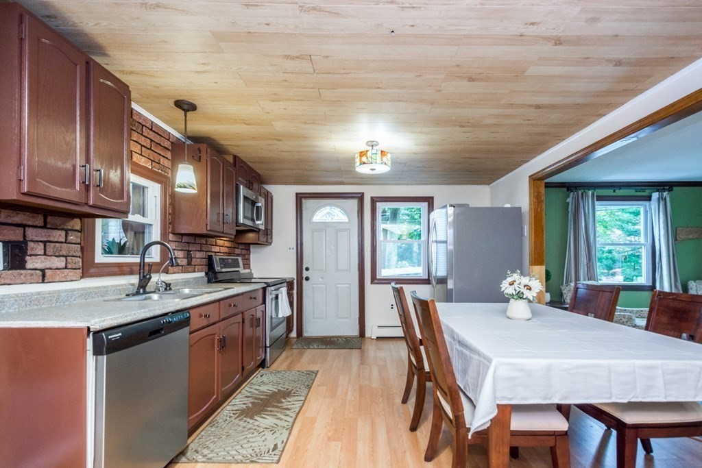 2 Lakeside Avenue Webster, MA 01570 - Photo 13 of 27 a kitchen with stainless steel appliances granite countertop a stove a sink dishwasher a dining table and chairs with wooden floor