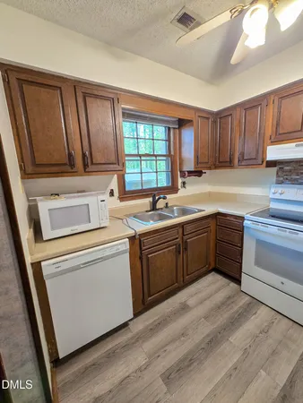 a kitchen with a sink wooden floor and a window