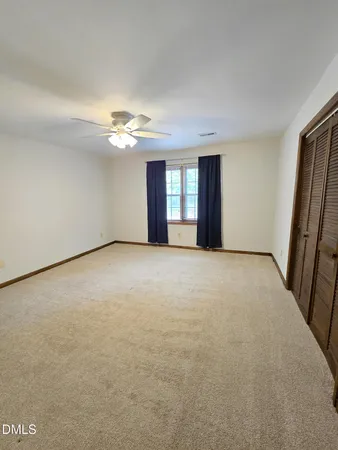 an empty room with windows and fan