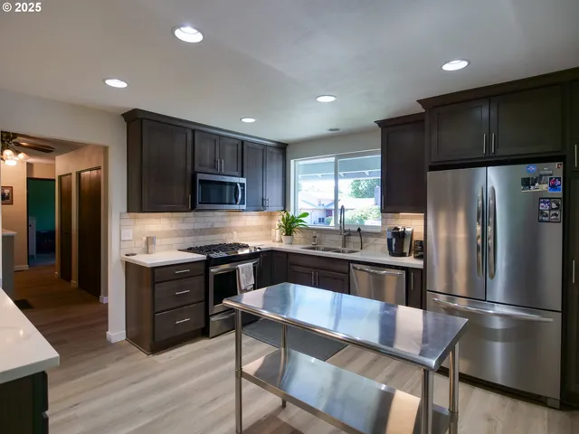 a kitchen with granite countertop a sink stove and refrigerator