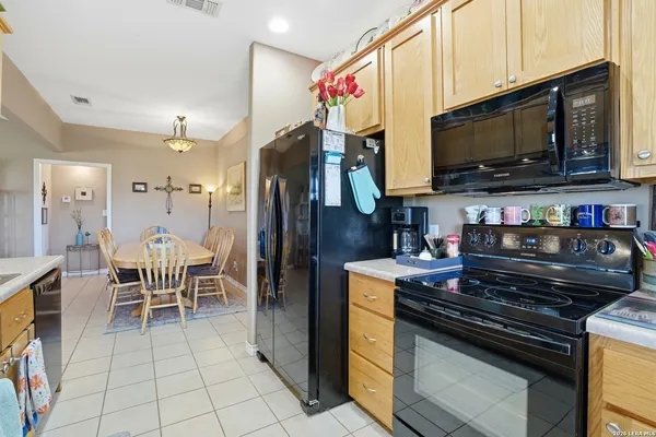 a kitchen with stainless steel appliances granite countertop a stove top oven a refrigerator a dinning table and chairs