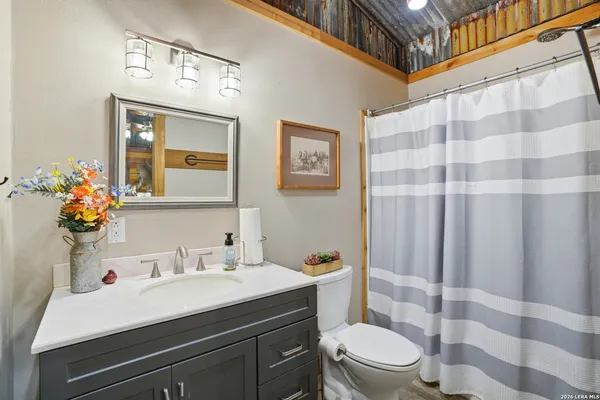 a bathroom with a sink a toilet a shower curtain and a mirror