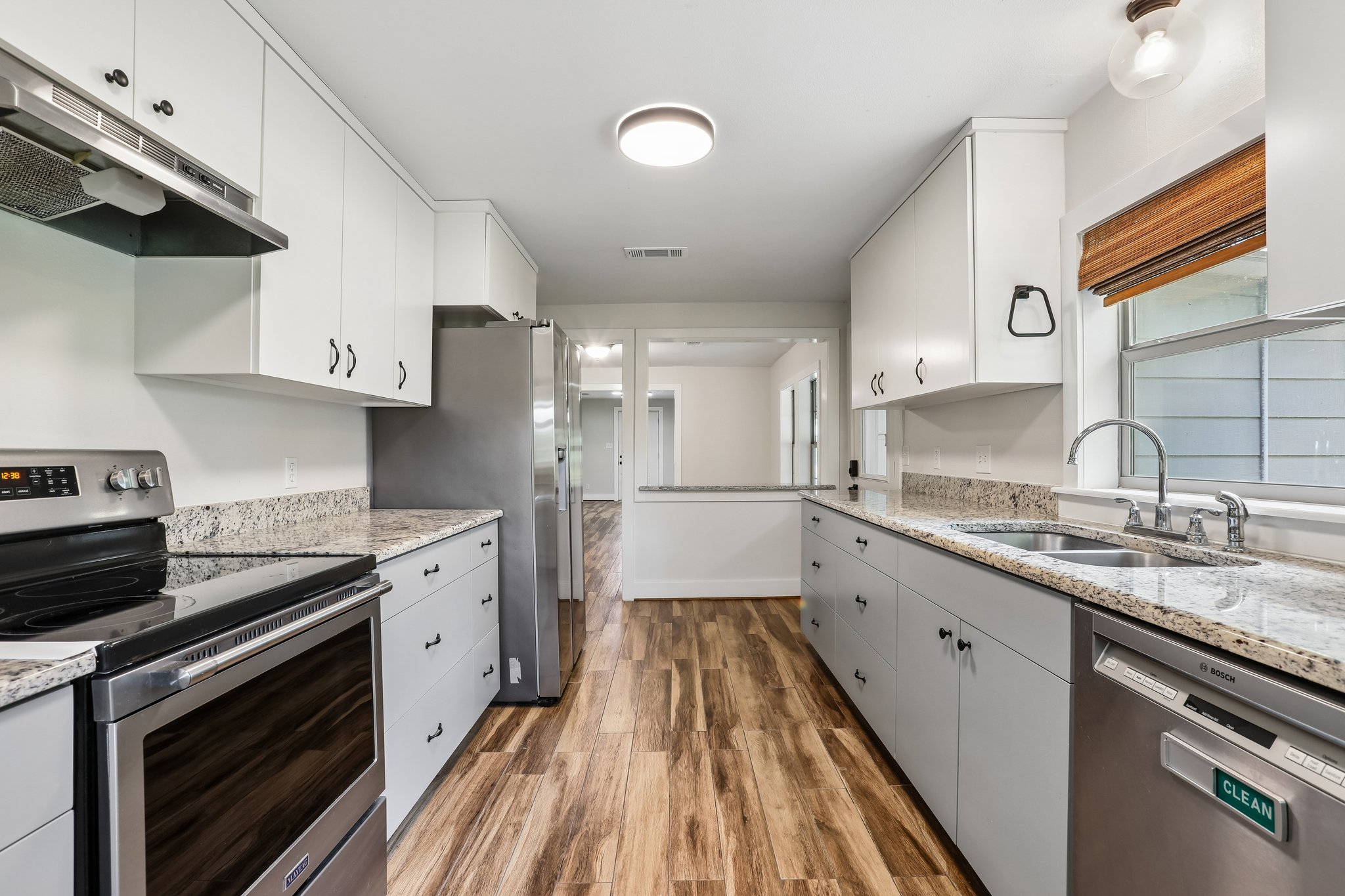 2089 Farm To Market Road 1704 Elgin, TX 78621 - Photo 10 of 31 A galley kitchen boasts sleek stainless steel appliances, granite countertops, and hardwood flooring.