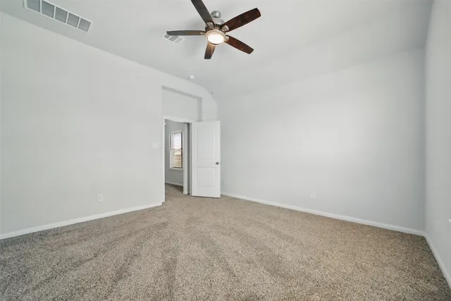 an empty room with a ceiling fan and carpet