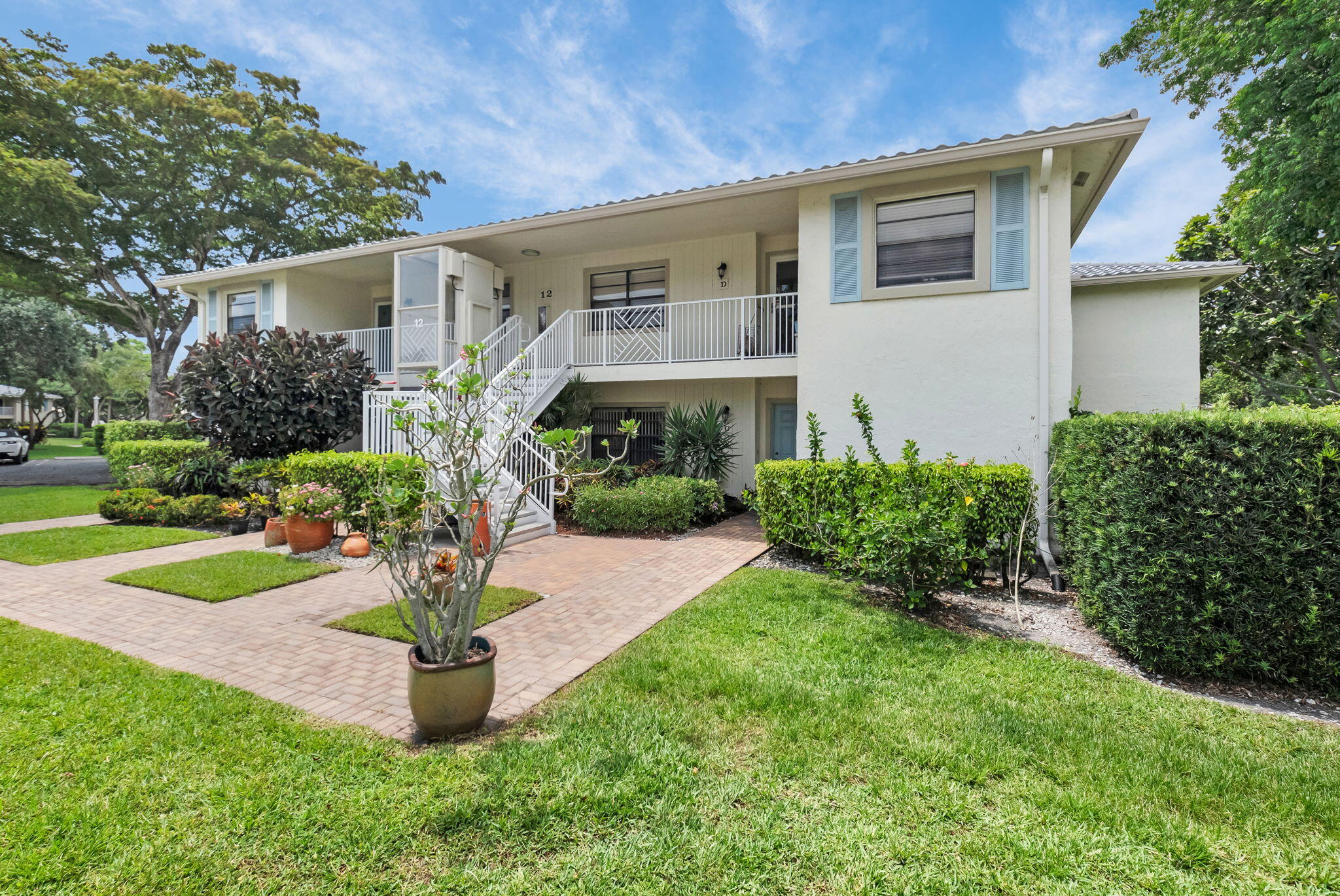 12 Westgate Lane, Unit C Boynton Beach, FL 33436 - Photo 2 of 54 a front view of a house with a yard and potted plants