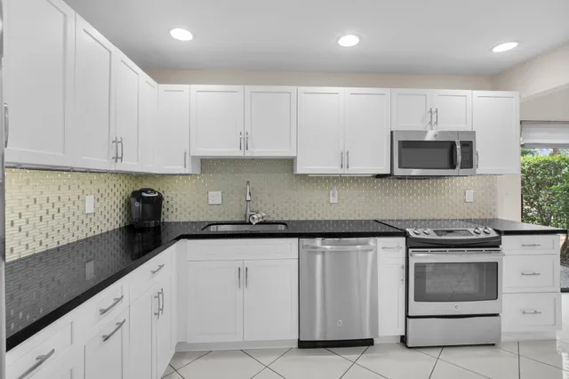 a kitchen with granite countertop white cabinets and stainless steel appliances