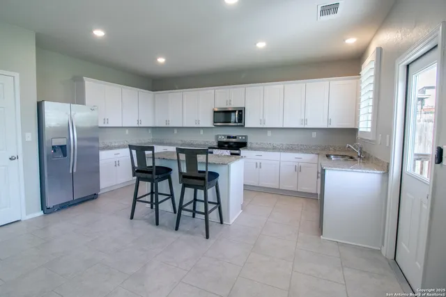 a kitchen with a table chairs refrigerator a sink and cabinets