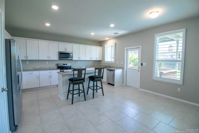 a open kitchen that has a lot of white cabinets and stainless steel appliances