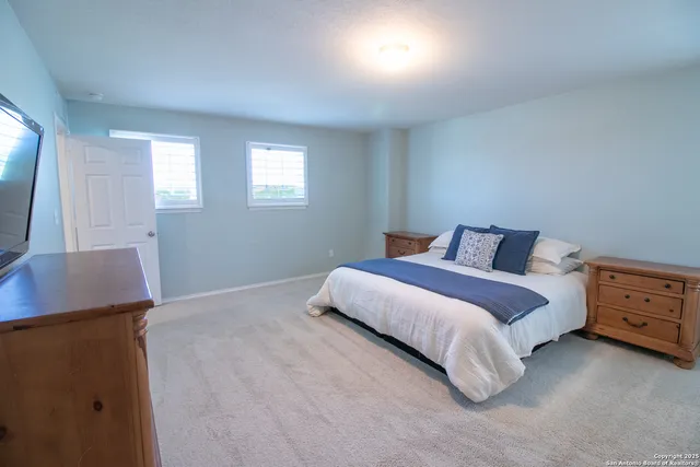 a bedroom with a bed and a flat tv screen on dresser