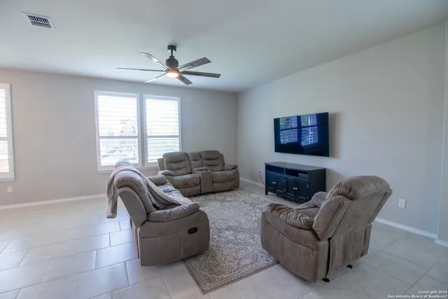 a living room with furniture a ceiling fan and a window