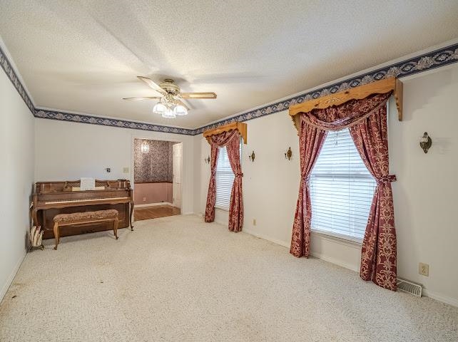 660 Hinton Road Counce, TN 38326 - Photo 13 of 40 Recessed window with blinds, ceiling fan with light fixture, wall sconces, patterned border trim, and a carpeted floor