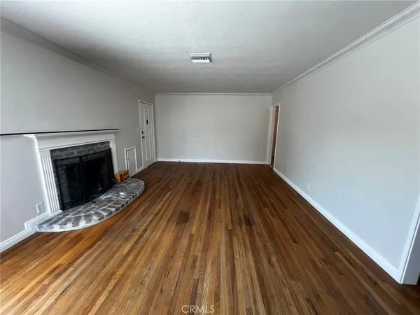a view of empty room with wooden floor and fireplace