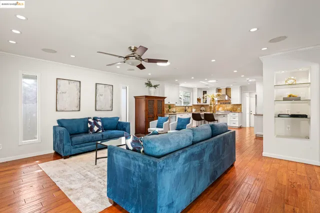 a living room with furniture kitchen view and a wooden floor