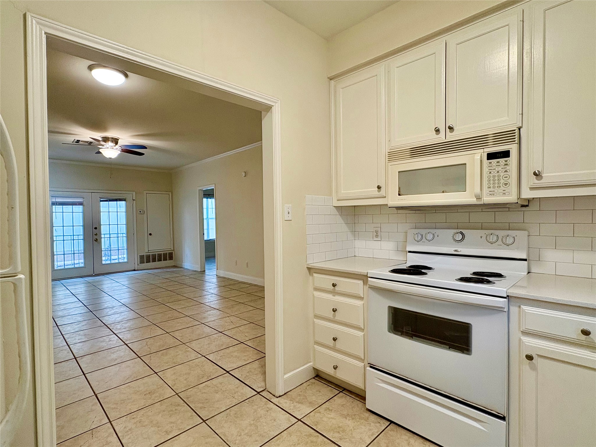 2100 San Gabriel Street, Unit 104 Austin, TX 78705 - Photo 4 of 8 Kitchen with white appliances, light tile patterned floors, french doors, decorative backsplash, and ceiling fan
