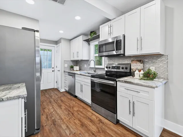 a kitchen with stainless steel appliances granite countertop a stove a sink and white cabinets