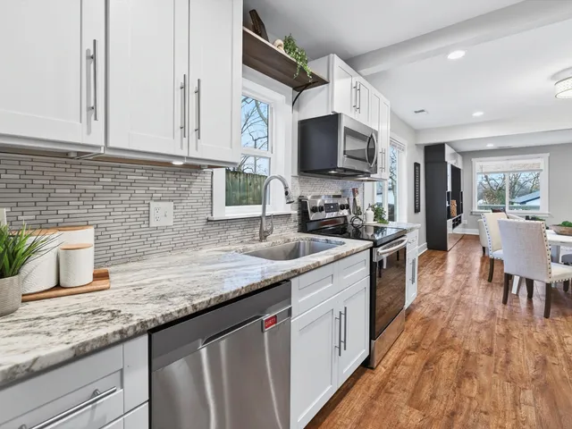 a kitchen with stainless steel appliances granite countertop a sink dishwasher stove and microwave with wooden floor