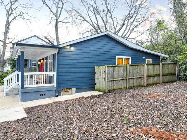 a view of a small house with a small yard and wooden fence