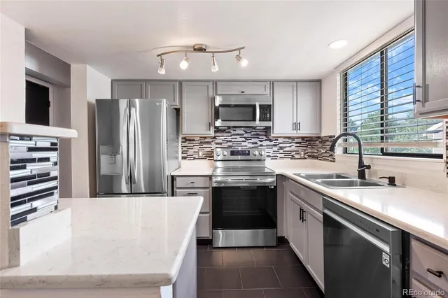 a kitchen with stainless steel appliances kitchen island granite countertop a sink stove and refrigerator