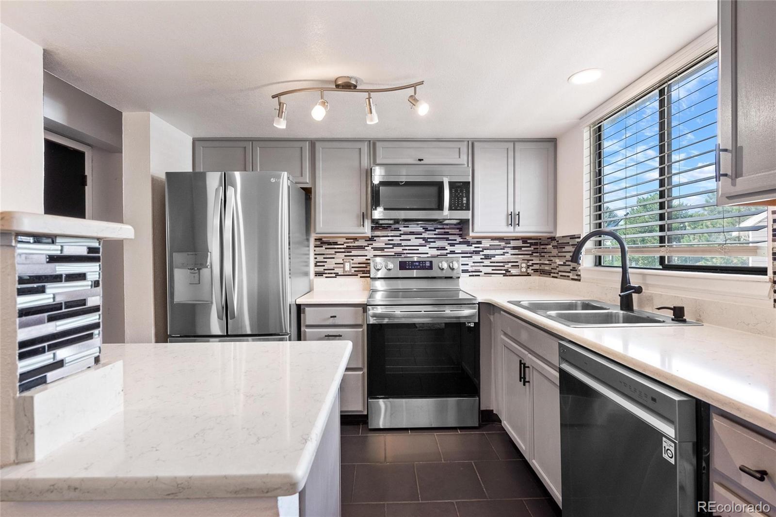 a kitchen with stainless steel appliances kitchen island granite countertop a sink stove and refrigerator