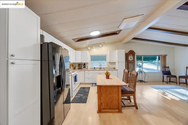 a kitchen with stainless steel appliances a refrigerator a stove a dining table and chairs with wooden floor