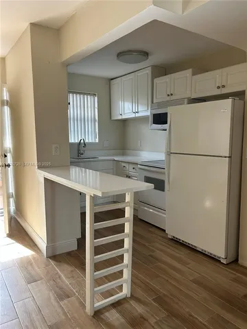 a kitchen with granite countertop a refrigerator and a stove top oven