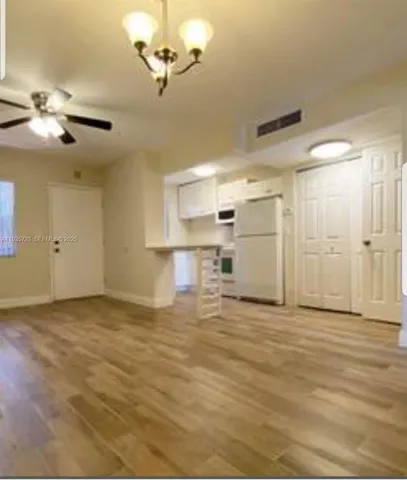 a view of a livingroom with a ceiling fan a kitchen space and a window