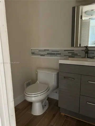 a bathroom with a granite countertop toilet a sink and mirror