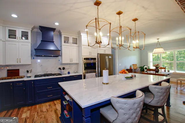 a kitchen with stainless steel appliances granite countertop a stove a refrigerator a kitchen island a sink dishwasher a dining table and chairs with wooden floor