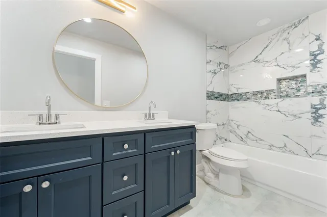 a bathroom with a double vanity sink toilet mirror and bathtub