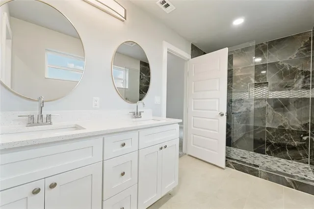 a bathroom with a double vanity sink mirror and shower