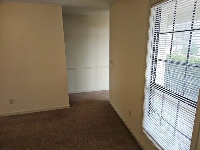 an empty room with a chandelier fan and windows