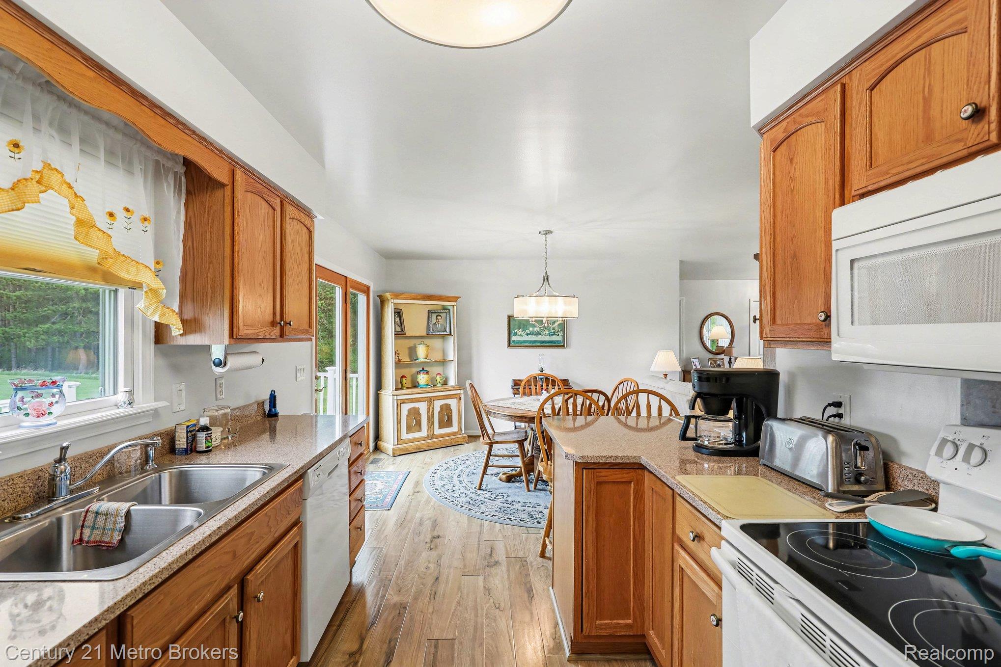 3861 5 Lakes Road Lapeer, MI 48446 - Photo 7 of 30 Kitchen with white appliances, wood finish cabinets, light wood-type flooring, pendant lighting, and a peninsula