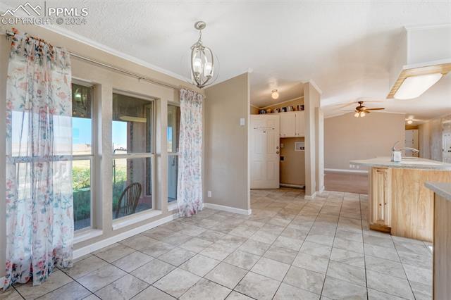 6240 Night Train Lane Yoder, CO 80864 - Photo 23 of 50 Kitchen with crown molding, light tile flooring, ceiling fan with notable chandelier, and pendant lighting