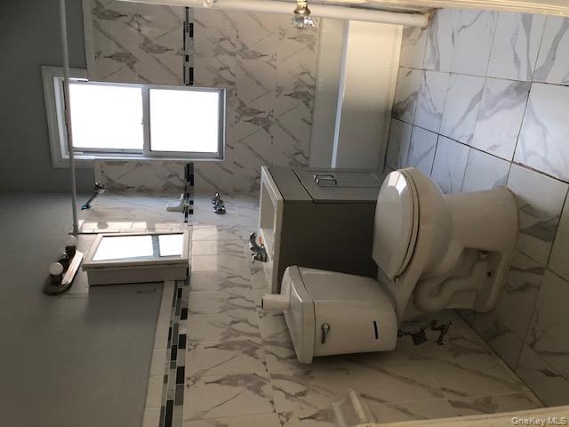 173-32 82nd Avenue Queens, NY 11432 - Photo 5 of 6 Bathroom featuring light marble finish floors, vanity, tile walls, and shower / tub combination