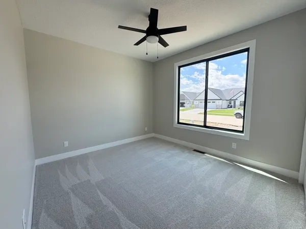 an empty room with windows and chandelier fan